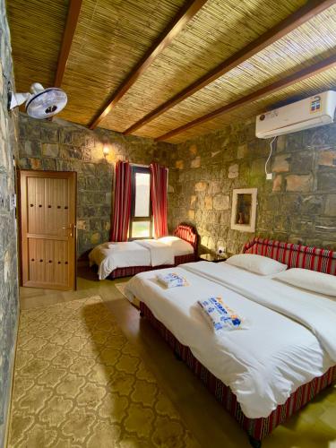 a bedroom with two beds and a stone wall at Jebel shams Sky in Misfāh