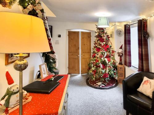 ein Zimmer mit einem Weihnachtsbaum und einem Schreibtisch mit einer Lampe in der Unterkunft Christmas Cottage in Cheddar