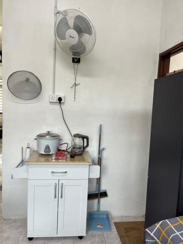 a kitchen with a white cabinet and a fan at Santai DPermai Homestay in Selama