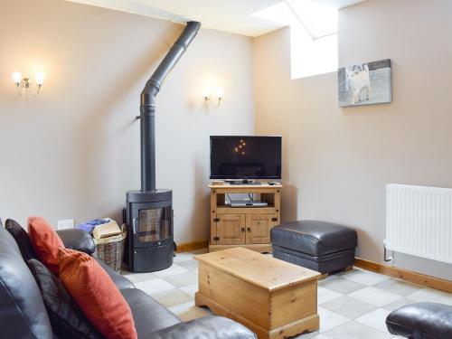 a living room with a couch and a wood stove at The Granary- Osc in Penbryn