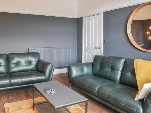 a living room with a leather couch and a table at Ty Isaf in Barmouth