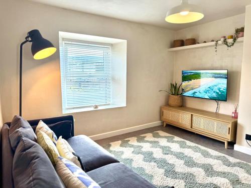 ein Wohnzimmer mit Sofa und Flachbildfernseher in der Unterkunft Palms 2 - Central, 5 mins walk to beach + parking! in Newquay