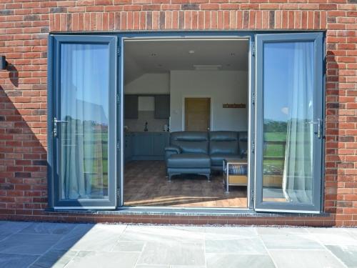 an open glass door with a chair in a brick building at Harry's Den in Chapel Saint Leonards