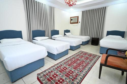 a hotel room with three beds and a rug at بيت سلسبيل in Al Madinah