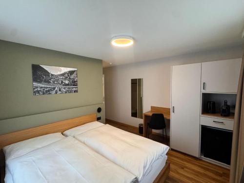 a bedroom with a white bed and a kitchen at Hotel R5 Budget - Chur in Chur