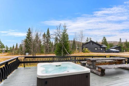 a hot tub on a deck with a wooden fence at Fagerasen 303 by Vacation Trysil in Mælem