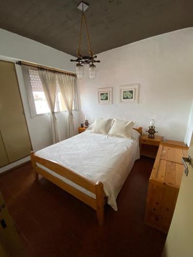 Un dormitorio con una cama blanca grande y una ventana en El lugar soñado, en Mar del Plata