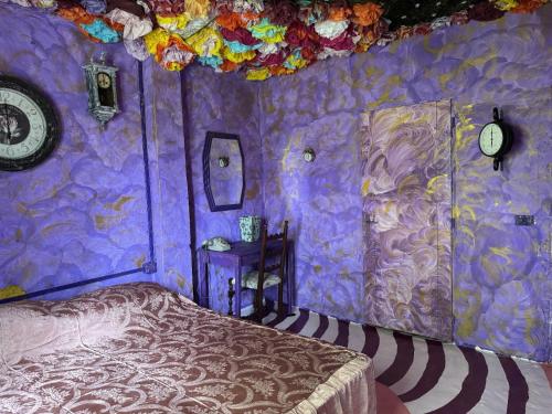 ein lila Zimmer mit einem Bett und einer Uhr in der Unterkunft Paciu Maison - Dimora Artistica Immersiva in Ozzano dell’Emilia