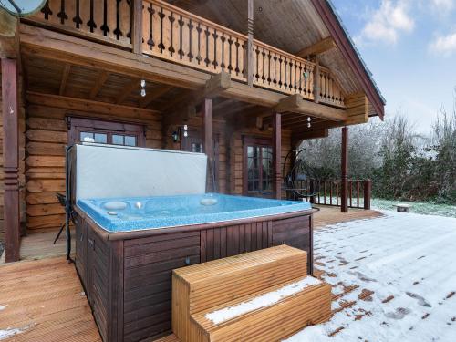 a hot tub on the deck of a log cabin at Ty Ceirios - Uk42100 in Carno
