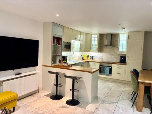 eine Küche mit einer Bar mit Hockern und einem Flachbild-TV in der Unterkunft Rosemarinus a Peaceful 4Bed 3Bath Townhouse Ballycastle in Ballycastle