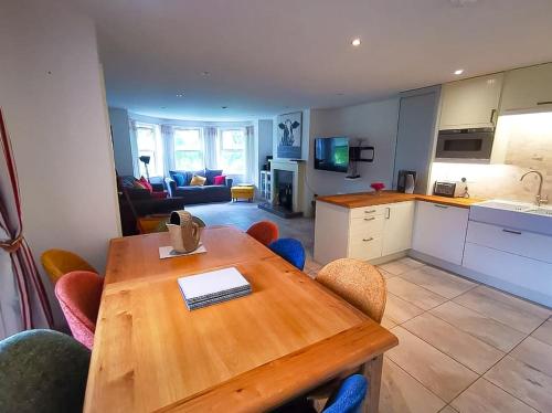ein Wohnzimmer mit einem Holztisch und einer Küche in der Unterkunft Rosemarinus a Peaceful 4Bed 3Bath Townhouse Ballycastle in Ballycastle