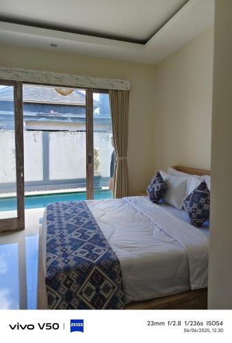 a bedroom with a bed and a large window at Villa kembar ungasan in Ungasan