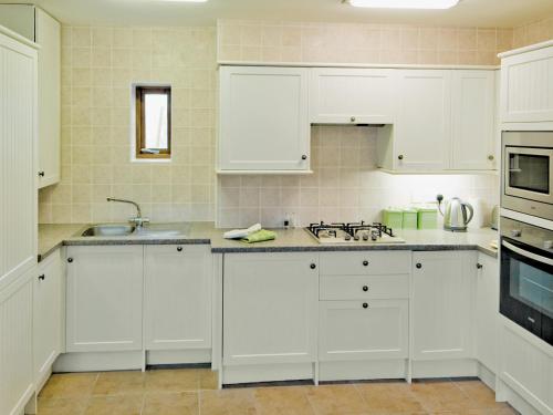 a white kitchen with white cabinets and a sink at Dairy Cottage - E5279 in Durham