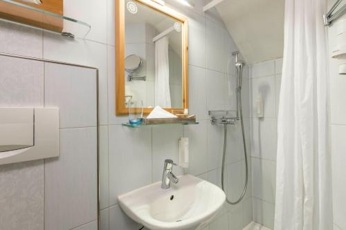 a white bathroom with a sink and a shower at Hotel R5 Budget - Chur in Chur