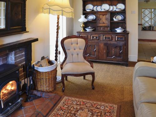 a living room with a chair and a fireplace at Nell's Cottage in Askam in Furness