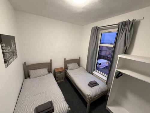 two beds in a room with a window at The Woodside in Cowdenbeath