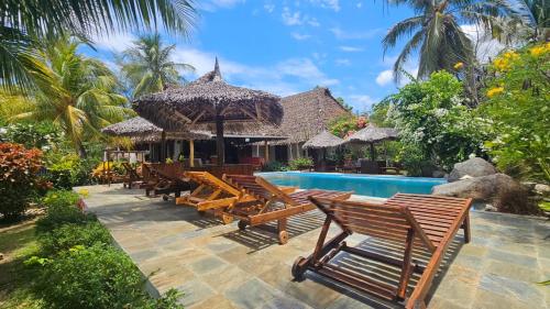 a resort with a swimming pool and wooden benches at La Vie Est Belle in Ambaro