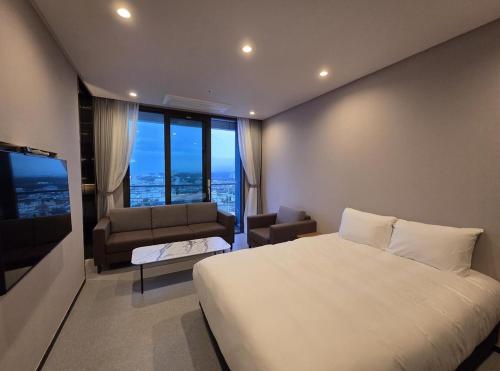 a bedroom with a large white bed and a couch at Nova Stay Gangneung in Chumunjin