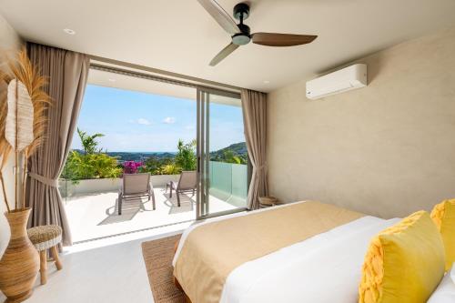 a bedroom with a bed and a balcony with chairs at Stunning Koh Samui Villa with Infinity Pool & Ocean View "Villa Sabaï Dii" in Koh Samui