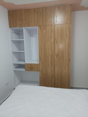 an empty bedroom with a bed and wooden cabinets at 1 bedroom BNB Meru in Meru