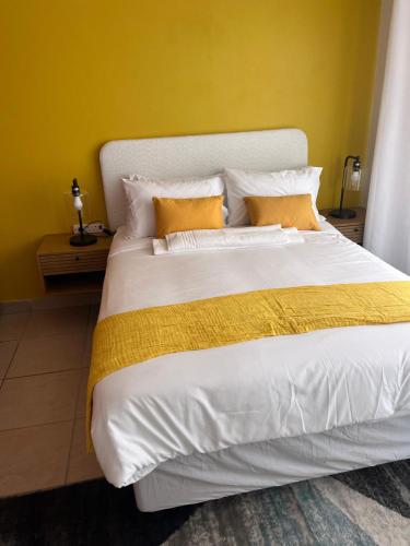 a bedroom with a large white bed with yellow walls at Waterfall Deluxe ll in Rustenburg