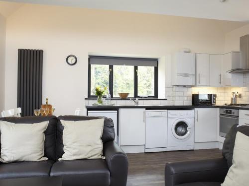 Una sala de estar con un sofá y una cocina. en Ash Barn - Fernhill Farm, en Ryde