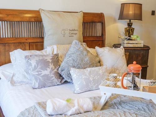 a bed with lots of pillows on it at The Saddler Cottage in East Boldon