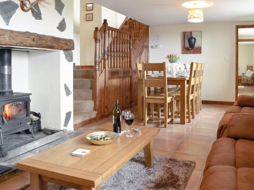 una sala de estar con una mesa y una chimenea en Ty Hir Bwlch Gwyn Farm Equestrian Centre, en Fairbourne