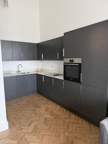 a kitchen with black cabinets and a wooden floor at Cosy one bedroom flat in the heart of Chelmsford in Chelmsford