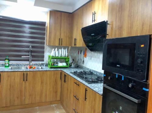 a kitchen with wooden cabinets and a black microwave at Debby Residence in Ijaiye