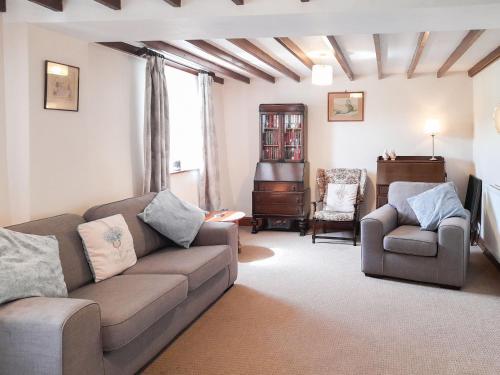 un salon avec un canapé et une chaise dans l'établissement Greenrigg Cottage, à Caldbeck