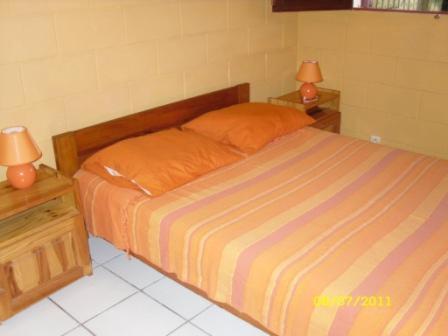 a bedroom with a bed with two lamps on night stands at laréunion in Maison Henou