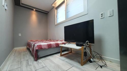 세인트빌리지 في Kup'o: غرفة نوم بسرير وتلفزيون وطاولة