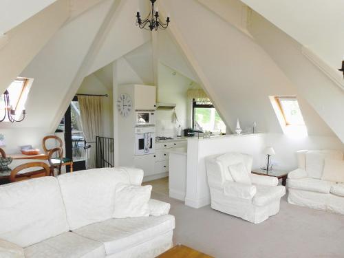 a living room with white furniture and a kitchen at Wigwam in Salcombe