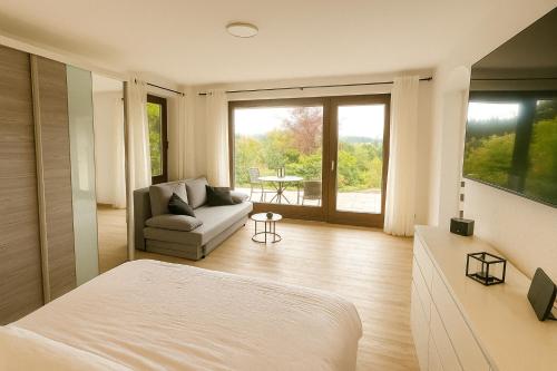 a bedroom with a bed and a couch and a table at Modernes Apartment mit 180° Bergblick in Buchenberg