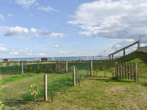een hek in een veld met de oceaan op de achtergrond bij Seascape in Sandown