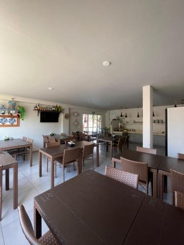 a dining room with tables and chairs and a kitchen at Chalé Murici Lençóis in Santo Amaro