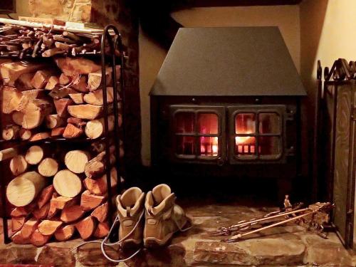 ein Kamin mit einem Stapel Holzscheite und Schuhen in der Unterkunft Heale Cottage - 28087 in Littleham