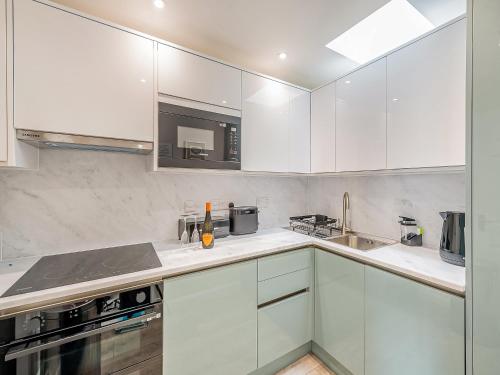 a white kitchen with white cabinets and a sink at Boohay - Bay Fort in Torquay