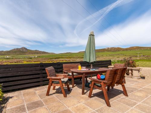 eine Terrasse mit einem Tisch und einem grünen Sonnenschirm in der Unterkunft Carn Llidi Cottage in St. Davids