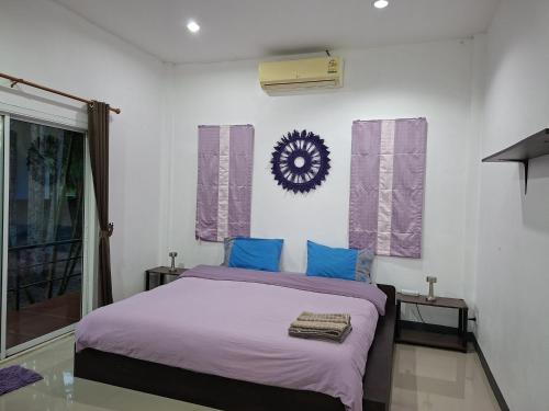 a bedroom with a bed with purple sheets and a clock on the wall at Little Purple House 2- AoNang in Ao Nang 