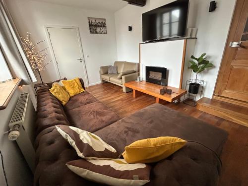 a living room with a couch and a tv at Maison de la Fontaine in Hierges
