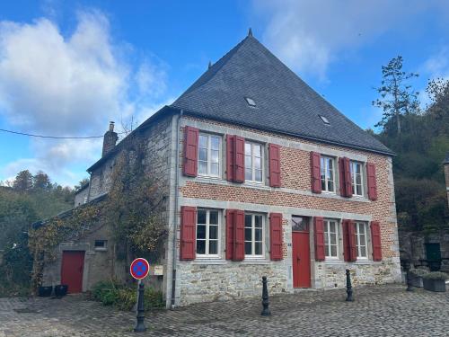 an old brick building with red shutters on it at Maison de la Fontaine in Hierges