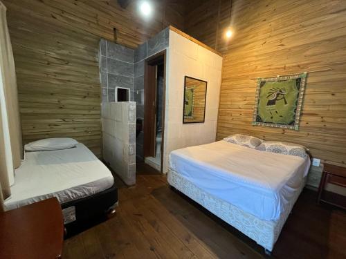a bedroom with two beds and a wooden wall at Voila Hostel in Florianópolis