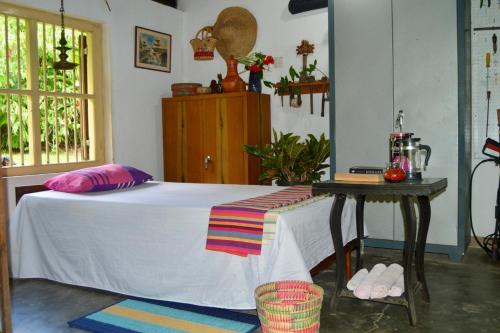 een slaapkamer met een wit bed en een tafel bij EcoBlueprint Garden in Pannala