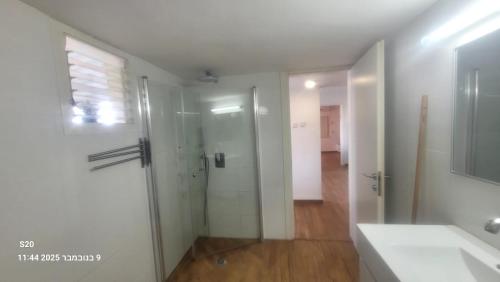 Un baño con ducha de cristal y lavabo. en Beit Nofesh, en Tiberíades