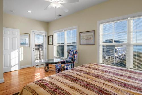 a bedroom with a bed and a table and windows at Second Row Stunning Ocean and Marsh Views in Holden Beach