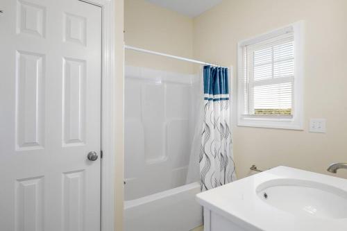 a white bathroom with a tub and a sink at Second Row Stunning Ocean and Marsh Views in Holden Beach