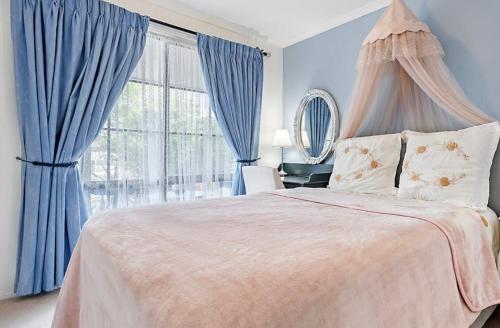 a bedroom with a large bed with blue curtains at Home of Susan Close in Narre Warren