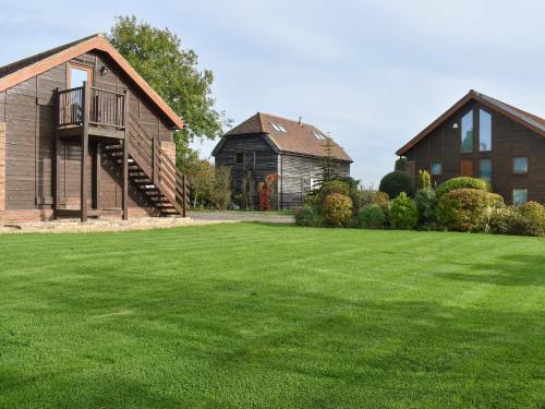 a house and a barn with a grass yard at Moorhens in Herstmonceux